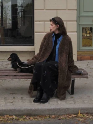 Brown oversized open-front faux shearling long coat for women shown in a side seated street style view
