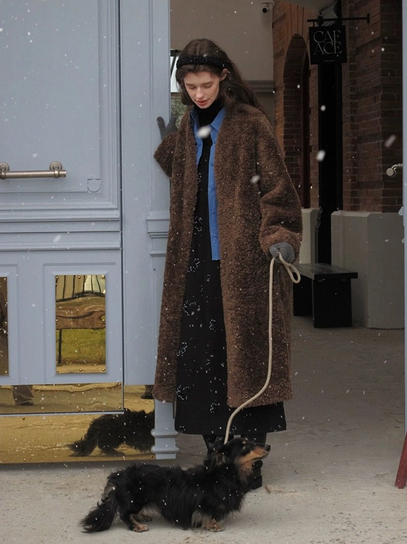 Brown oversized open-front faux shearling long coat for women styled for a snowy winter street walk