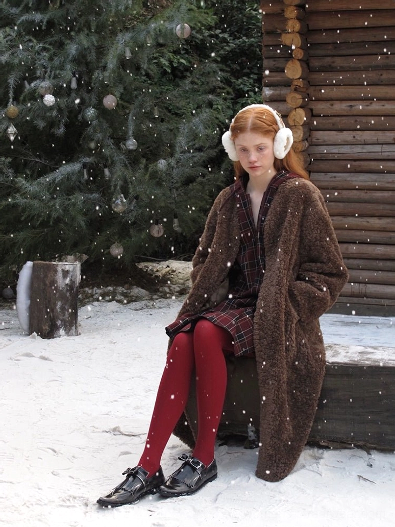 Brown oversized faux shearling long coat with collarless open front styled over a plaid dress in winter