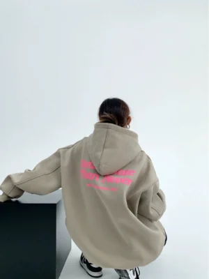 Gray green oversized pullover hoodie back view with attached drawstring hood and partial pink slogan graphic in modern Seoul streetwear style