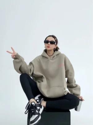 Gray green oversized graphic hoodie front three quarter view with pink chest print kangaroo pocket dropped shoulders and relaxed Korean streetwear fit
