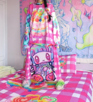 Oversized pink gingham streetwear sweater styled with colorful paneled sleeves and coordinated casual outfit in a playful bedroom setting