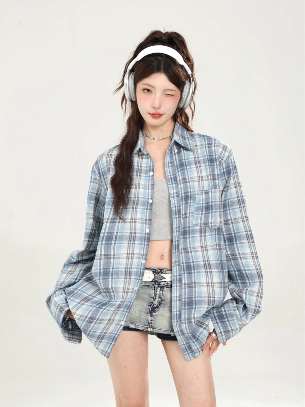 Blue plaid loose button-down shirt layered over a crop top and denim shorts for Y2K streetwear styling