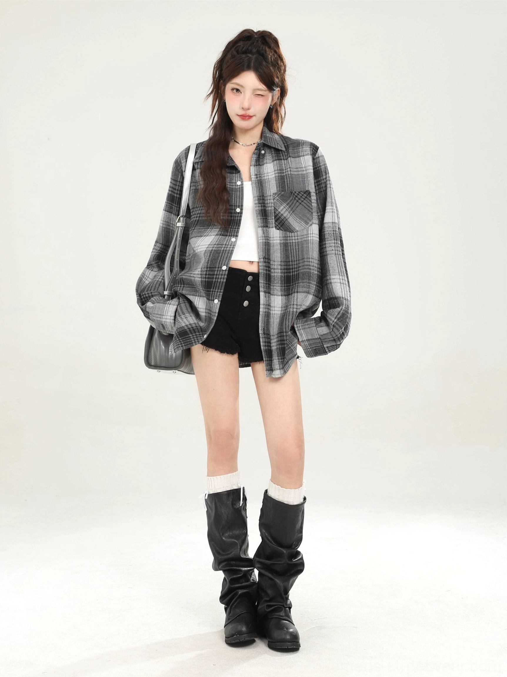 Dark plaid oversized button-down shirt styled with black shorts knee-high boots and shoulder bag