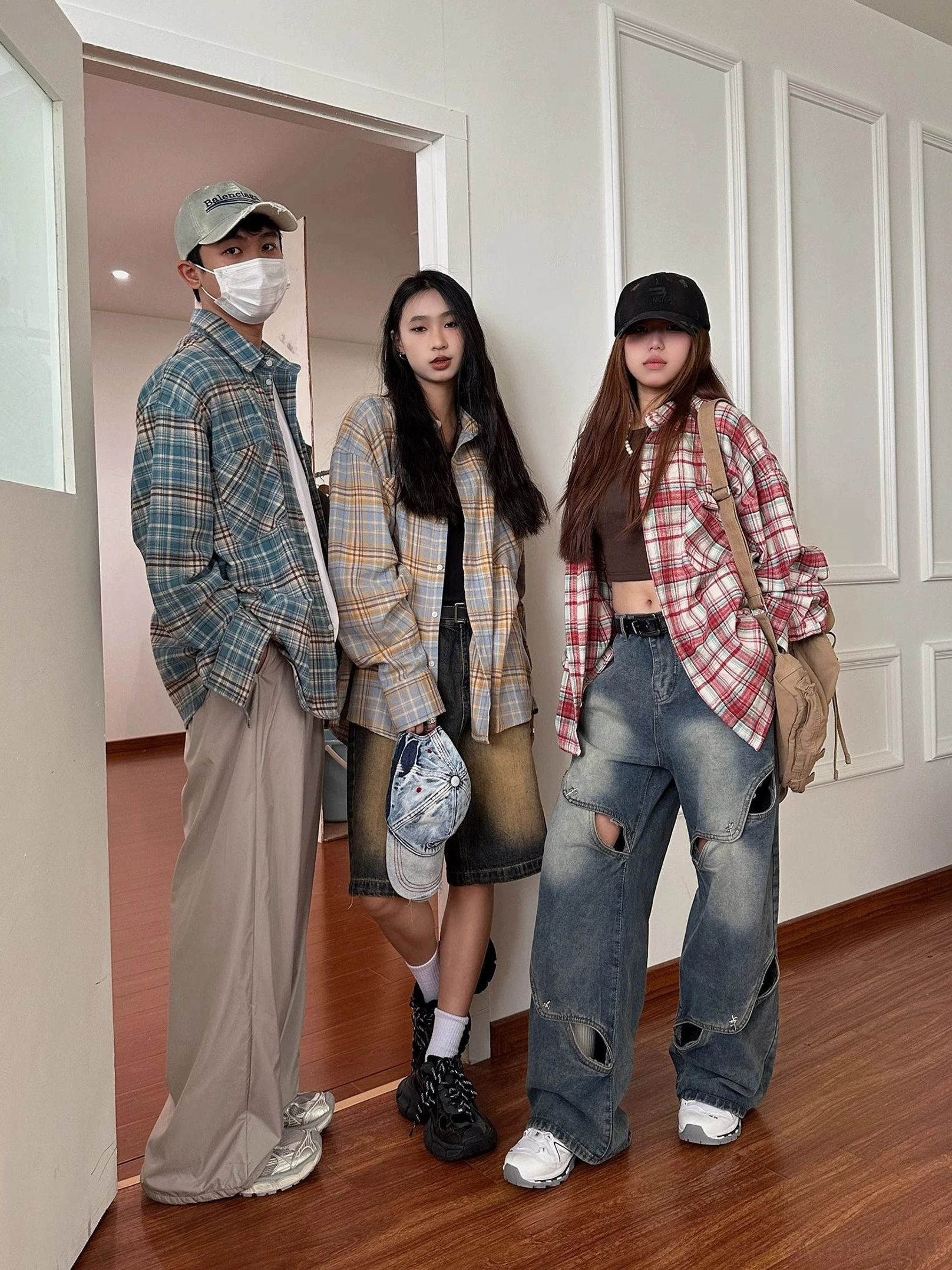 Three people wearing relaxed oversized plaid flannel shirts in a casual Korean streetwear group look