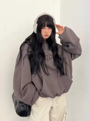 Oversized plumped logo hoodie dark gray front view with subtle tonal P chest logo on female model in minimalist white studio