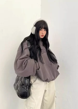 Dark gray oversized hoodie three-quarter side view female model with quilted black shoulder bag and white cargo pants