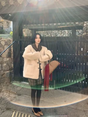 Front view of a beige oversized reversible sherpa button jacket with fluffy fleece texture, dark contrast collar, toggle fasteners, and relaxed women's streetwear fit
