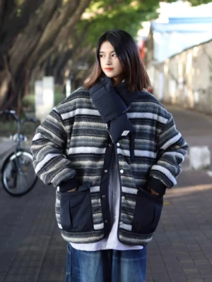 Full body view of oversized reversible striped quilted winter coat with snap buttons drop shoulders and front patch pockets on a riverside bike lane