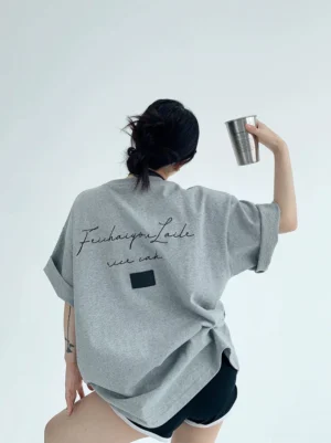 Heather gray oversized script back drop-shoulder cotton T-shirt with cursive lettering, square patch, rolled cuffs, and black shorts