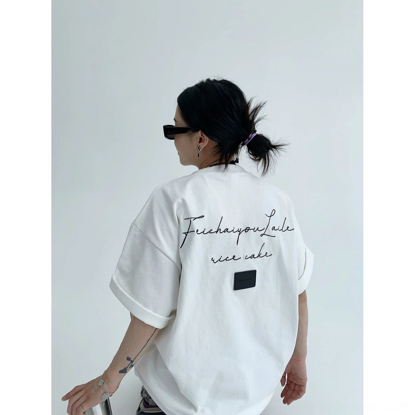 Bright white oversized script back T-shirt on female model showing cursive lettering, square patch, relaxed rolled sleeves, and Korean street style