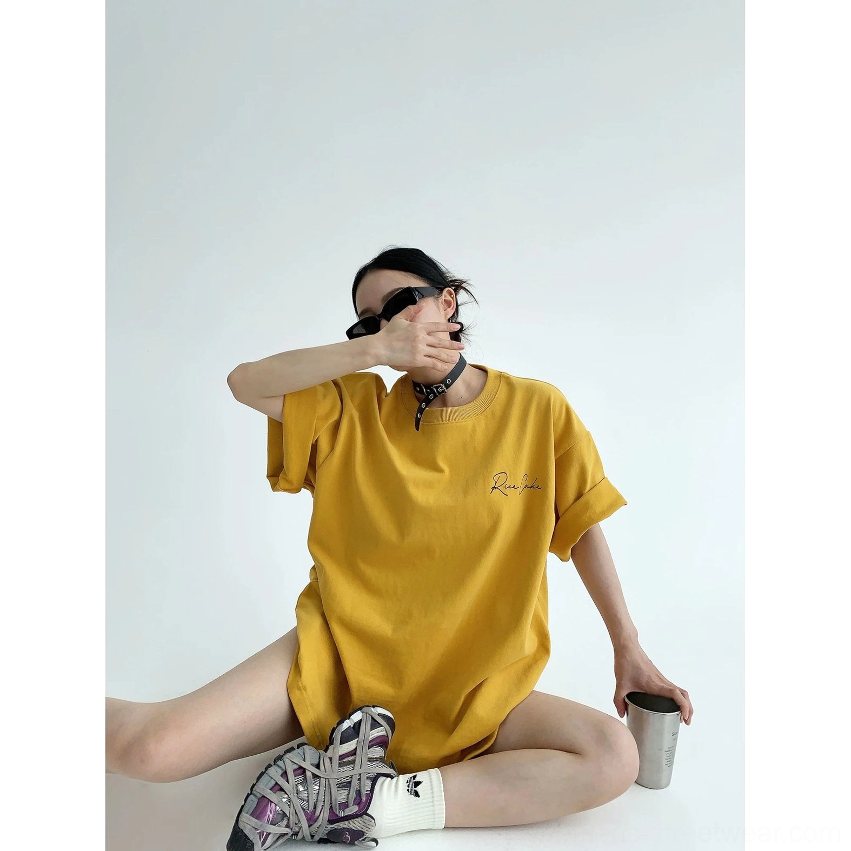 Mustard yellow oversized script streetwear T-shirt with front and back lettering, square patch, rolled cuffs, choker, and chunky sneakers