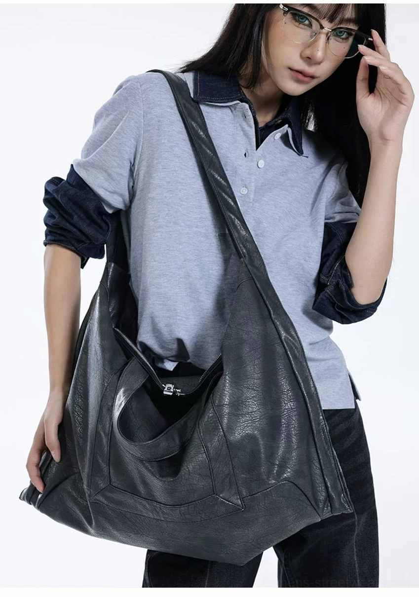 Oversized Shadow Drape slouchy PU leather tote bag worn crossbody with grey polo shirt and dark jeans
