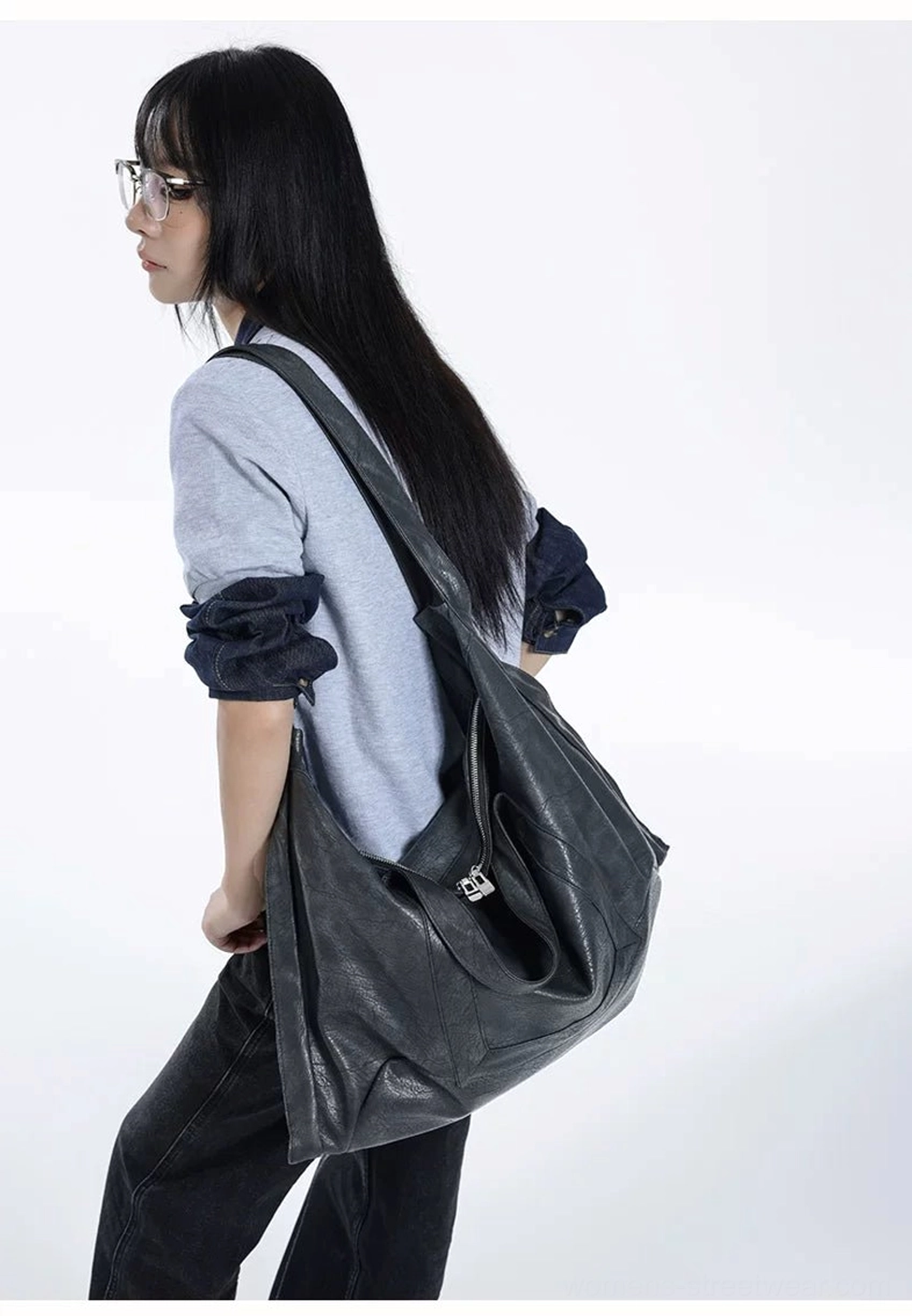 Side profile of oversized Shadow Drape slouchy tote bag with soft faux leather folds and metal hardware detail