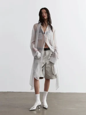 Women's oversized sheer streetwear blouse styled with cargo shorts and silver heeled ankle boots