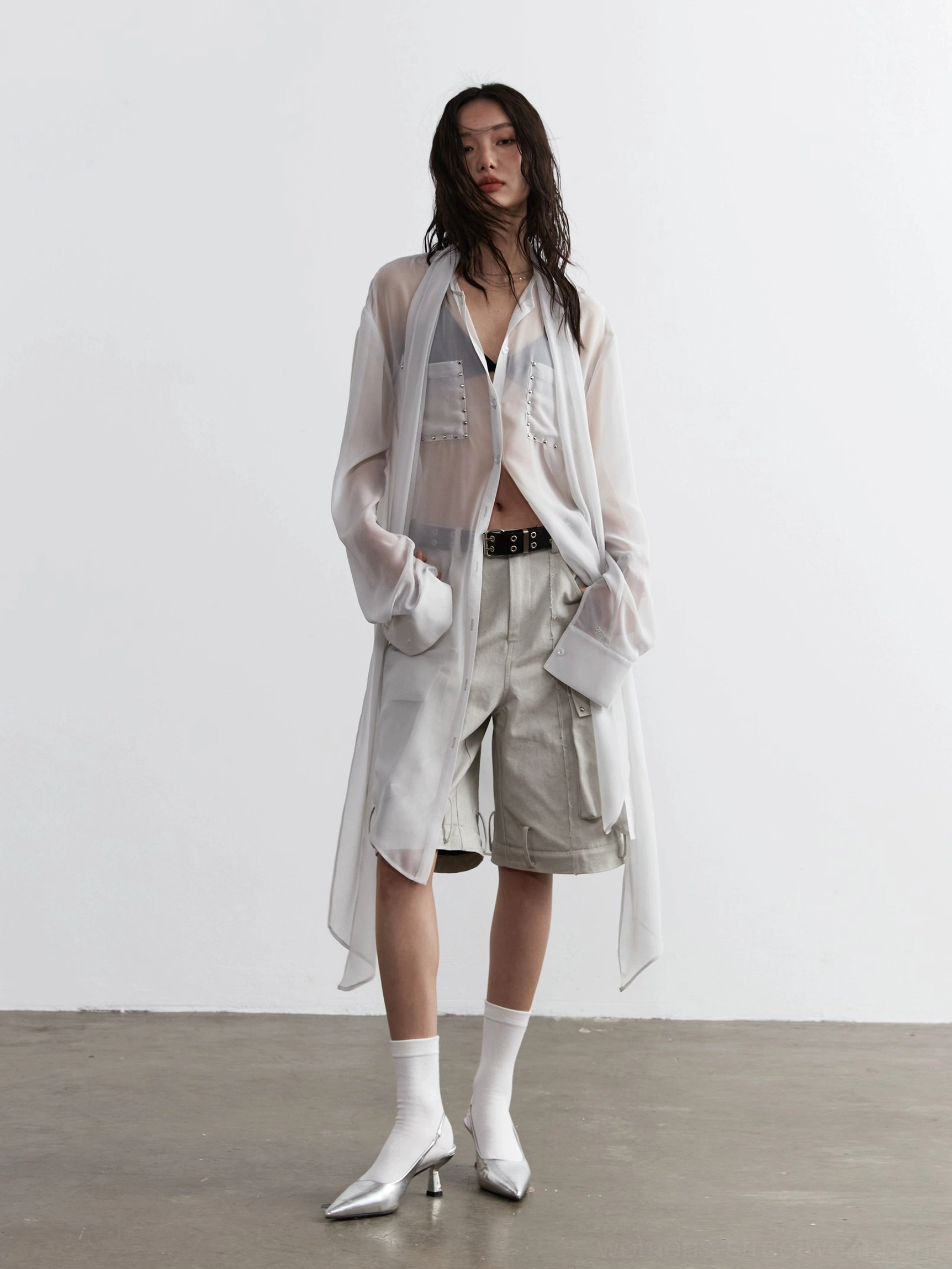 Women's oversized sheer streetwear blouse styled with cargo shorts and silver heeled ankle boots