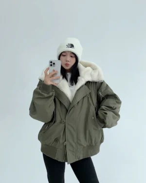 Army green oversized sherpa-lined bomber jacket with off-white faux-shearling hood lining shown in a front mirror selfie