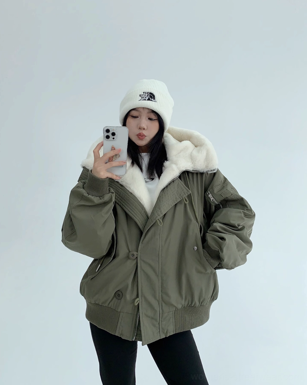 Army green oversized sherpa-lined bomber jacket with off-white faux-shearling hood lining shown in a front mirror selfie