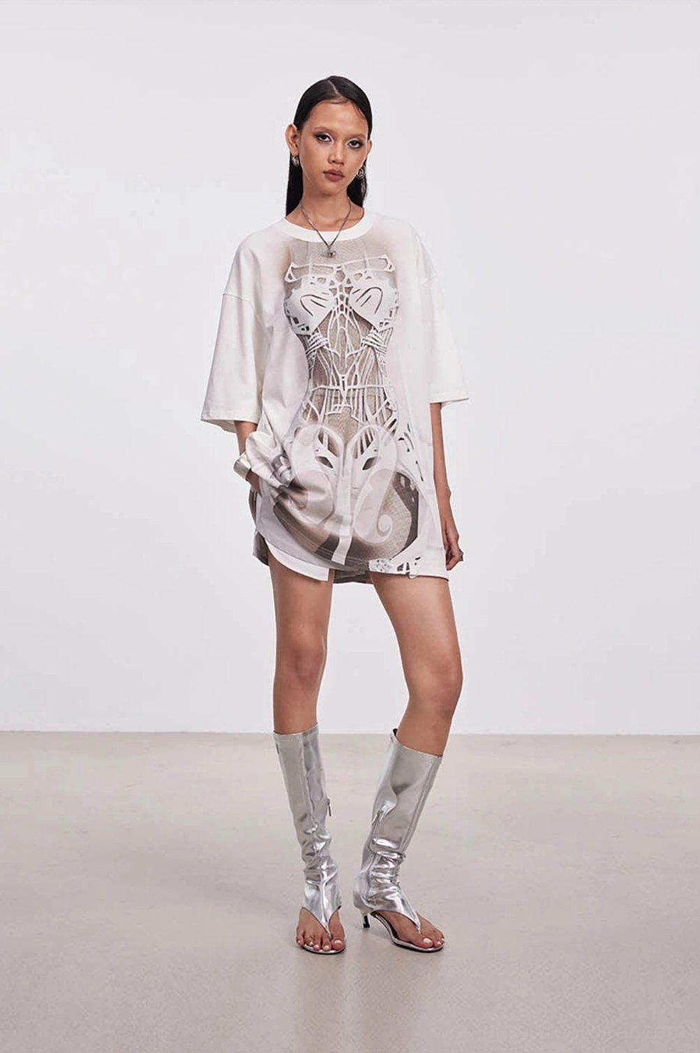 Full-body styling of an oversized skeleton graphic tee dress worn with silver metallic heeled boots in a streetwear outfit