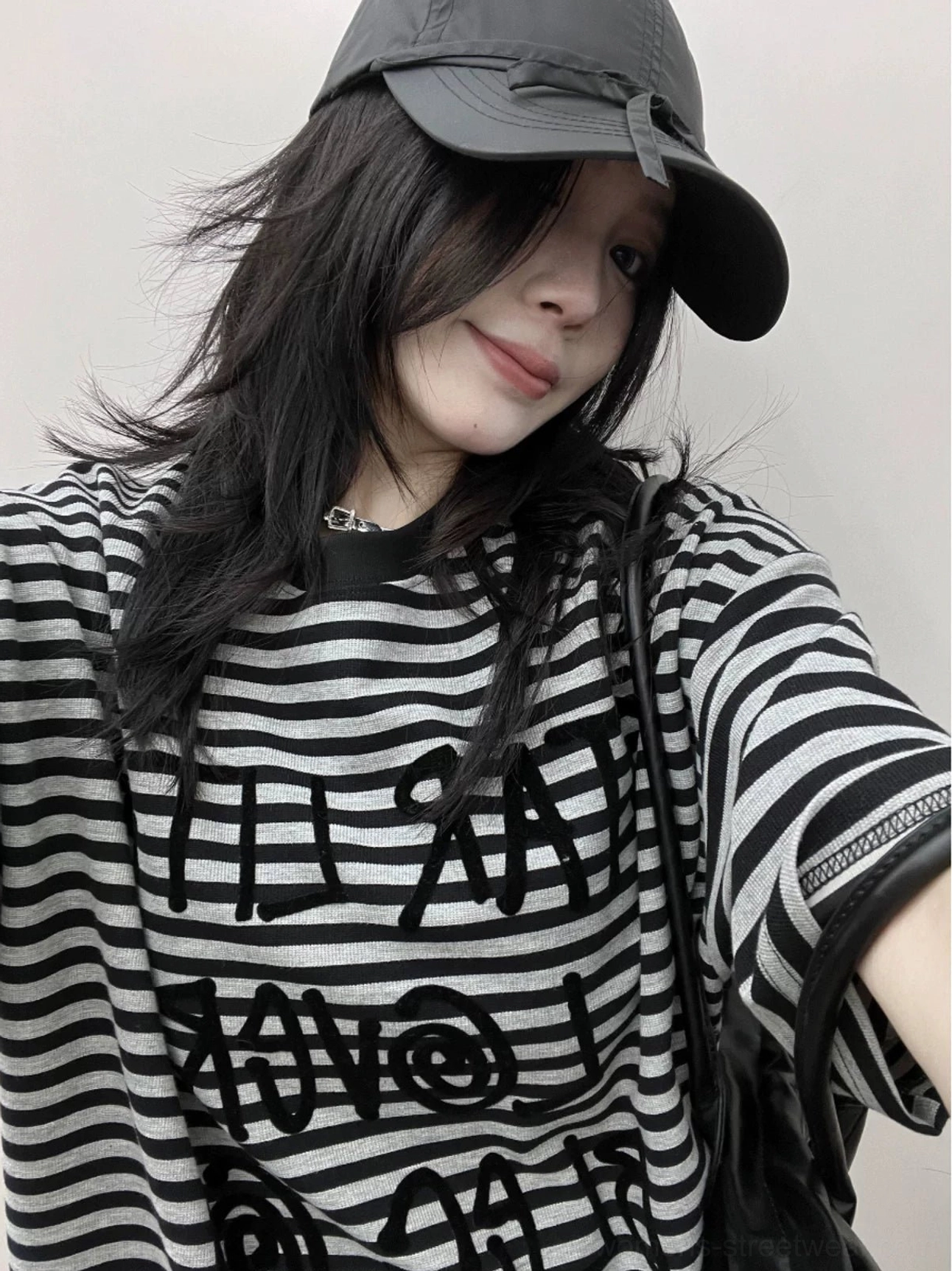 Close-up front view of an oversized striped cotton jersey T-shirt showing raised reverse lettering and soft graphic stripe details