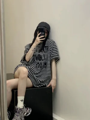 Side-back view of an oversized striped graphic T-shirt with rolled short sleeves, loose boxy fit, and casual Korean streetwear styling