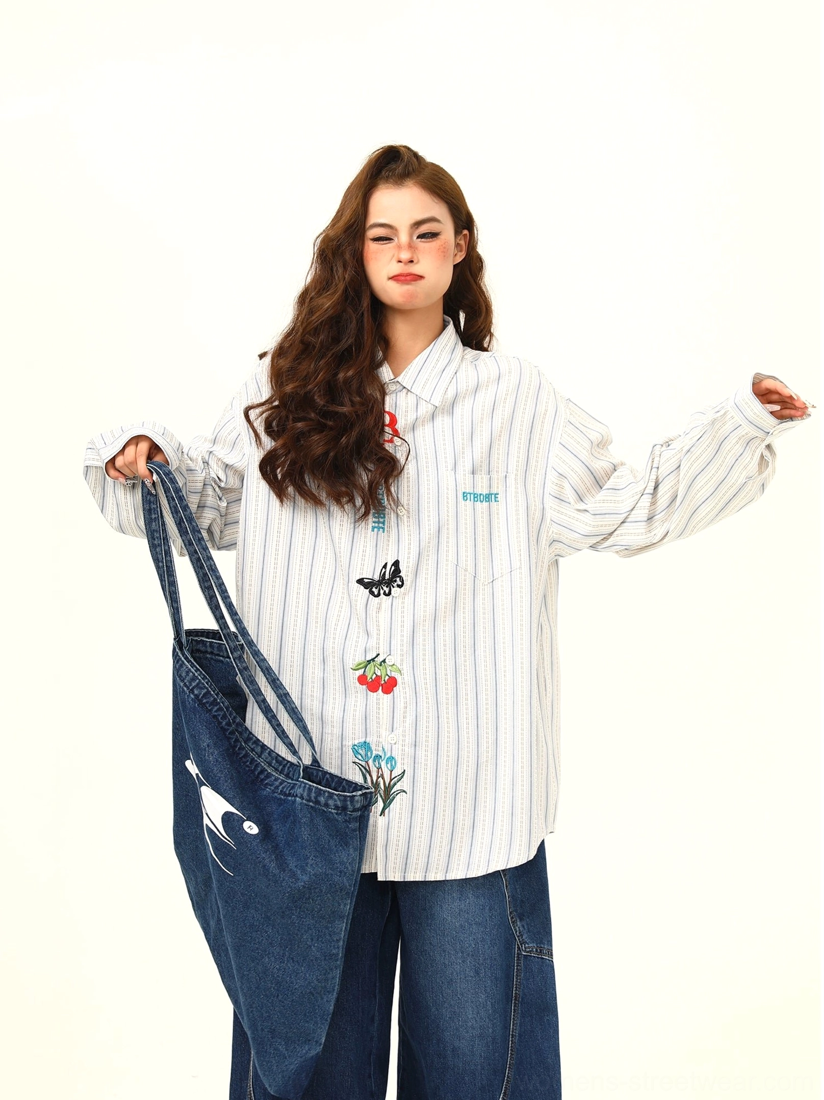 Three-quarter view showing the long loose sleeves classic collar and colorful embroidery on an oversized white gray striped shirt
