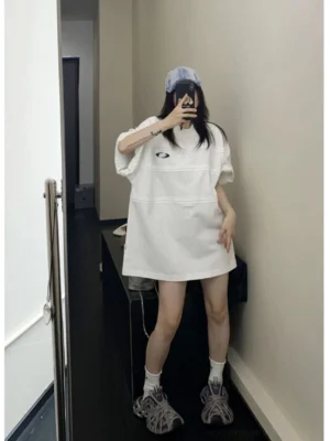 Full body view of white oversized track panel jersey tee with horizontal tuck seams and oval chest embroidery