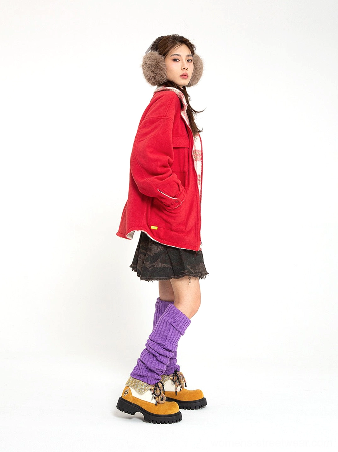 Female model wearing oversized two-tone work boots with a red coat, mini skirt and purple leg warmers