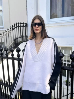 Front view of oversized color block V-neck racing stripe sweater with light body black sleeves and contrasting sleeve stripes
