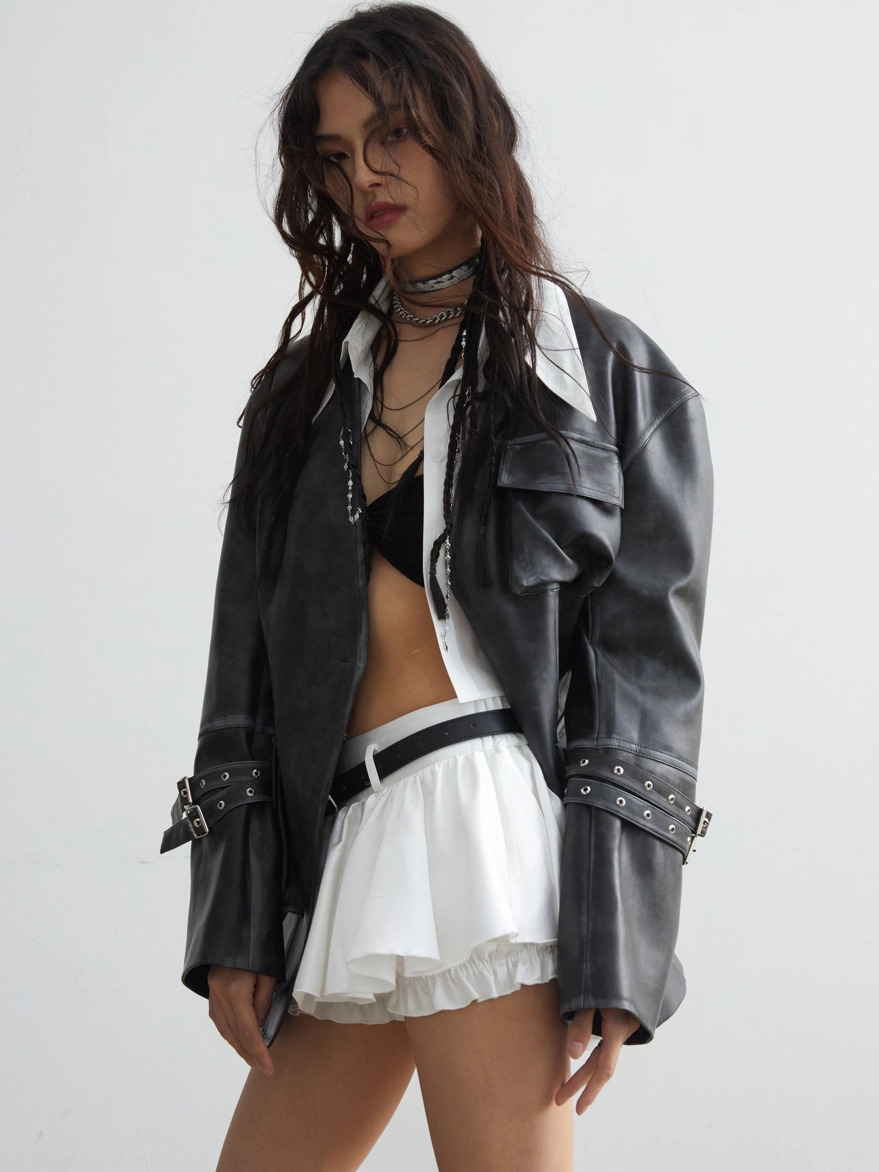 Oversized faded black-grey PU leather jacket worn open with utility pockets, adjustable buckle cuffs, and relaxed Korean streetwear styling