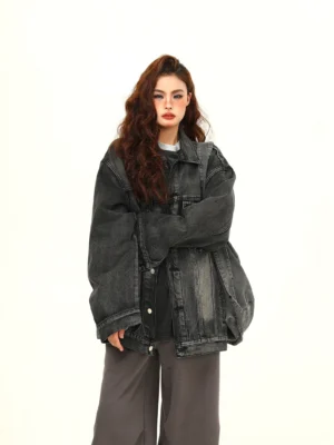Three quarter view of a relaxed oversized vintage denim jacket with drop shoulders and distressed washed texture styled with gray wide leg trousers