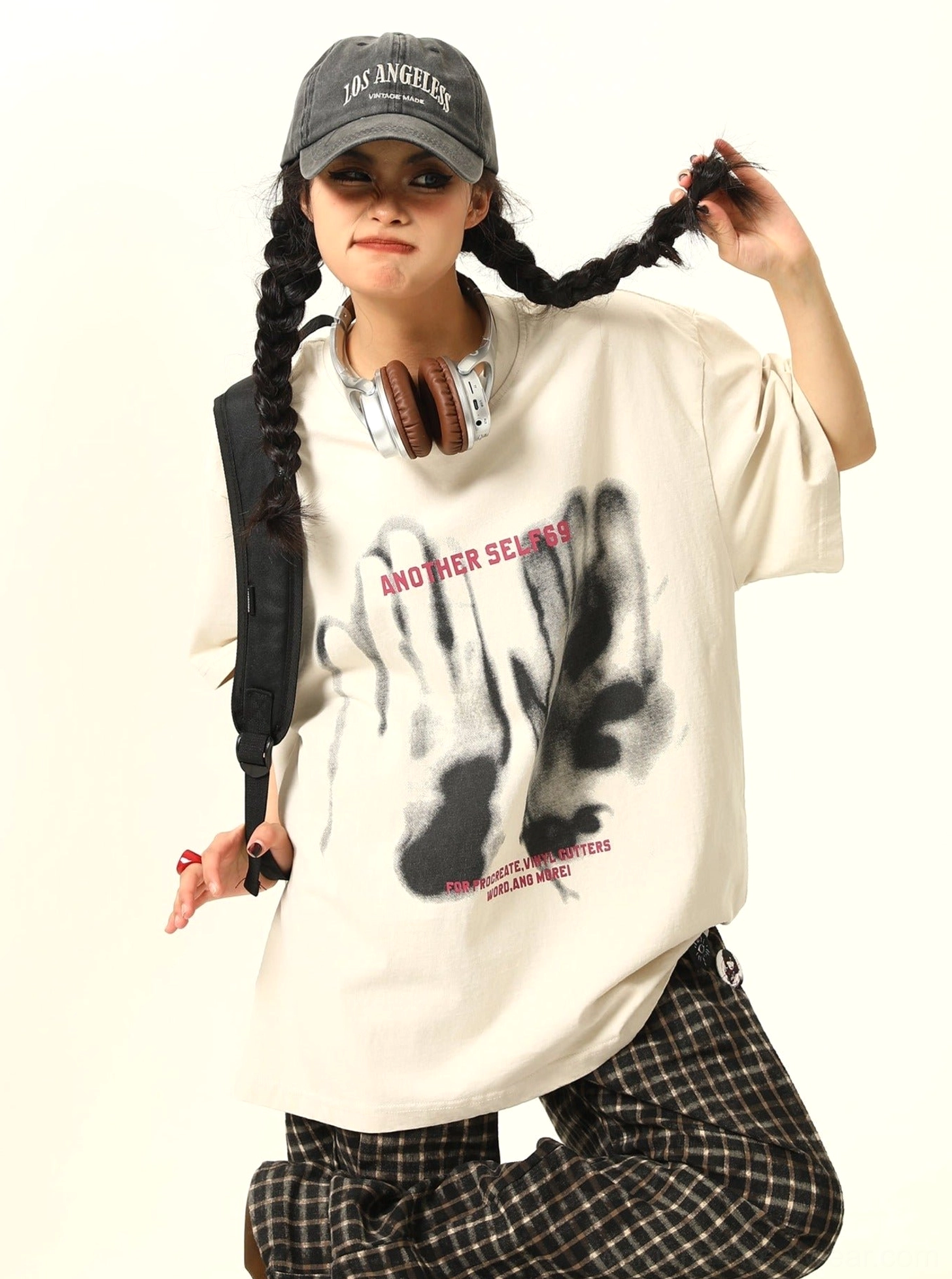 Apricot oversized washed handprint grunge graphic T-shirt styled with plaid pants and backpack