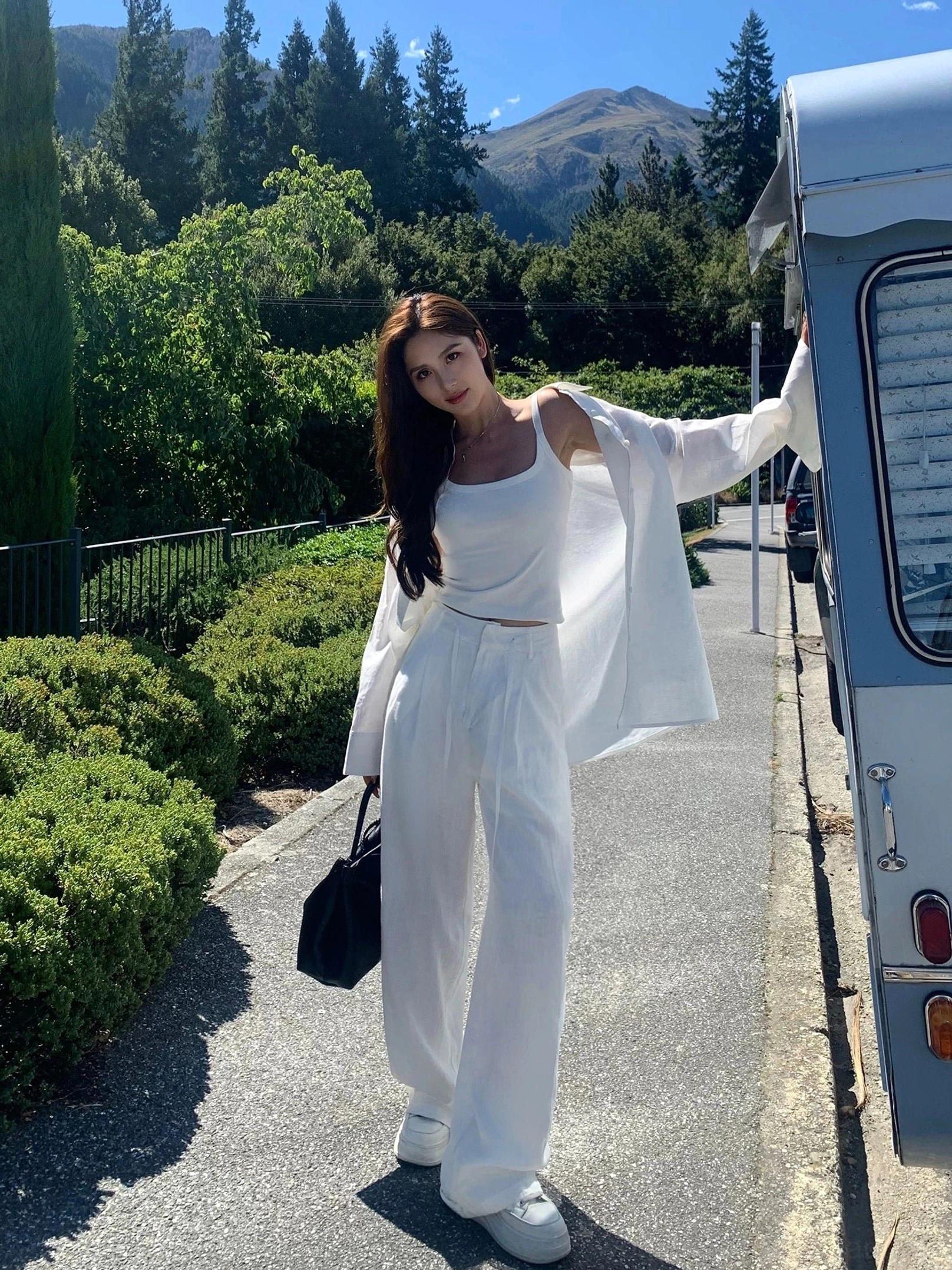 Oversized white linen three-piece casual outfit set side profile, high-waisted wide leg pants with relaxed fit linen shirt on forest country road