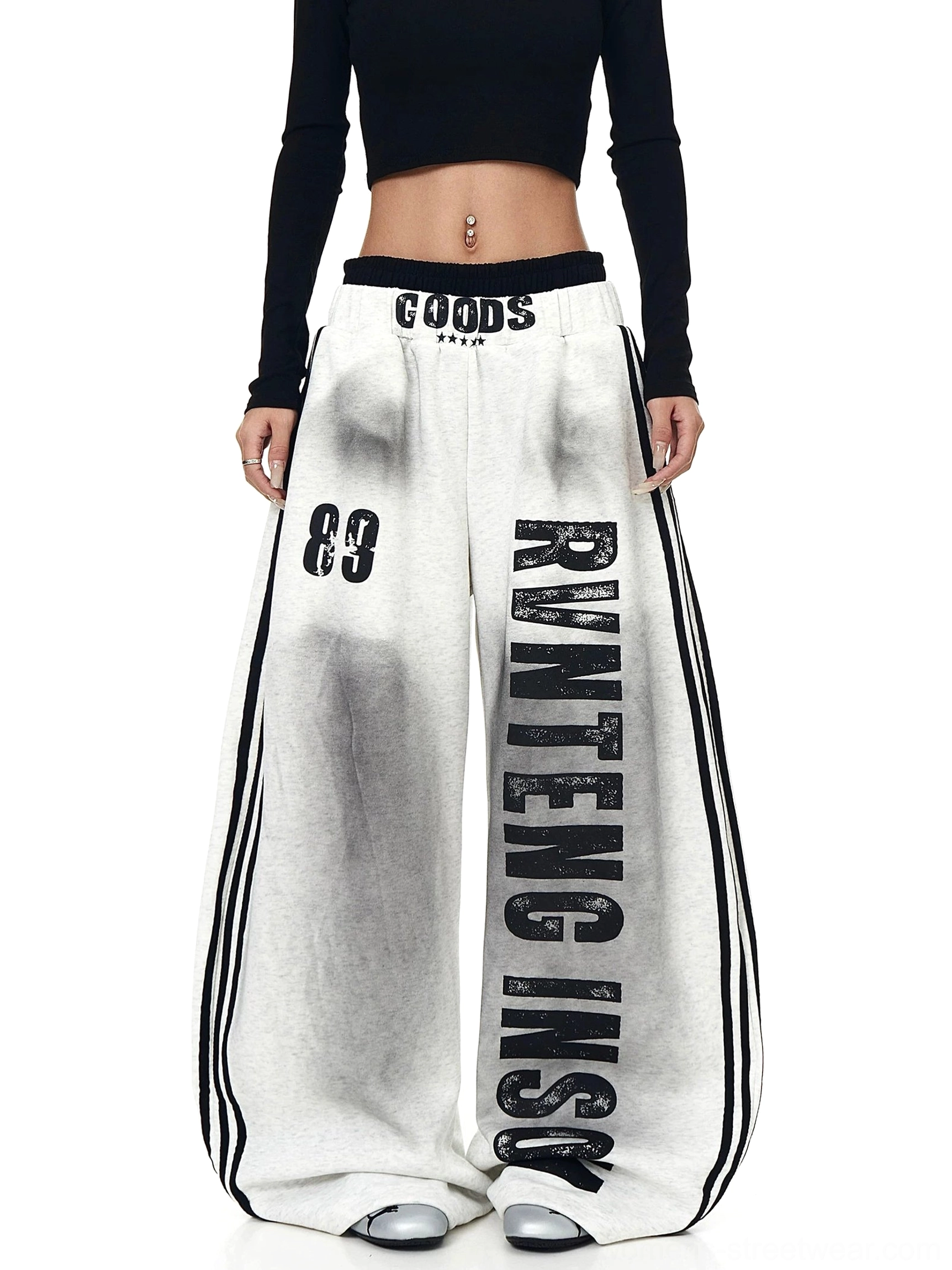 Heather gray oversized wide-leg graphic fleece sweatpants styled with a black cropped top, vertical varsity lettering, 89 graphic, and striped streetwear details