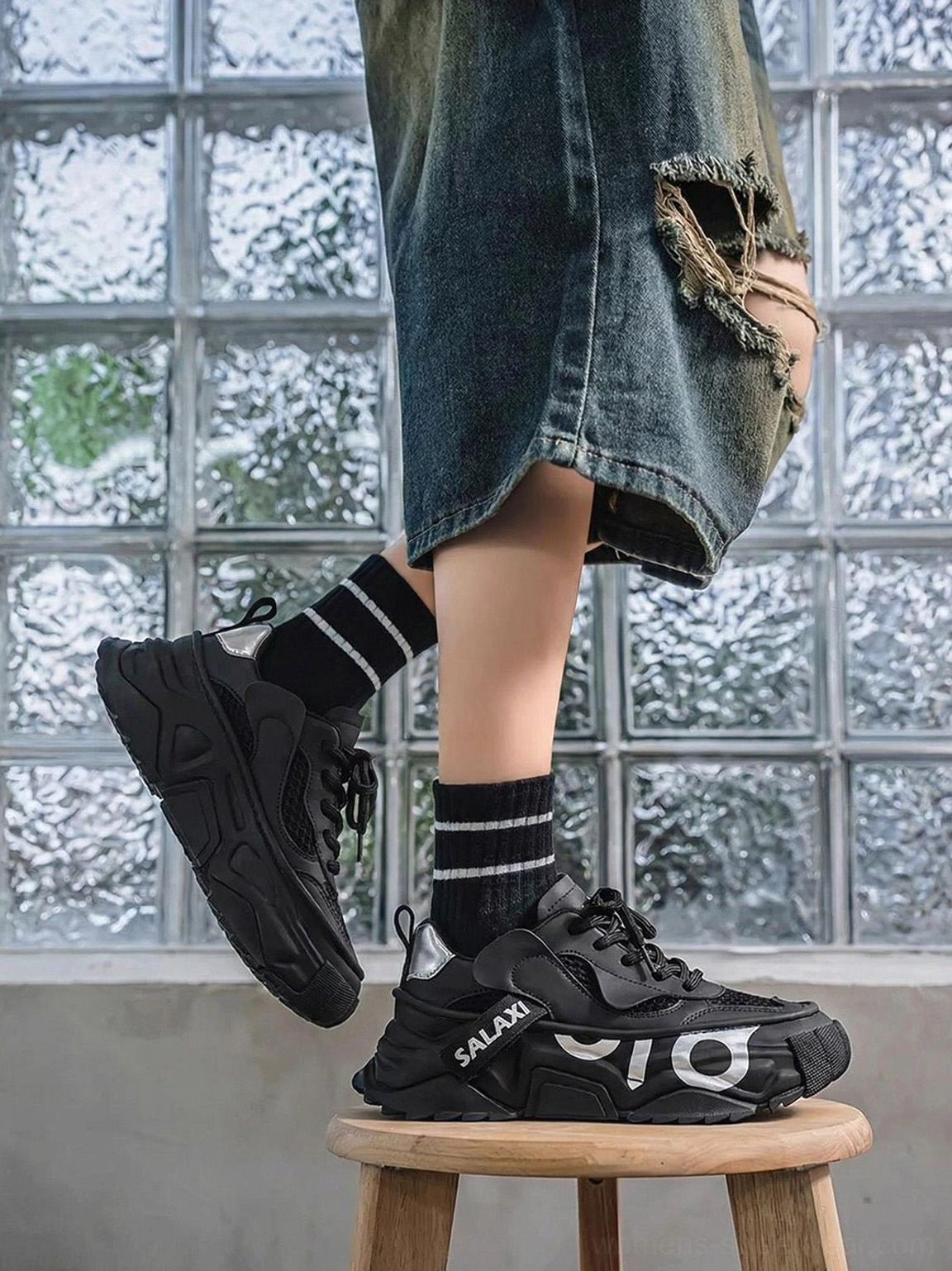 OWL 3.0 black chunky platform sneakers on foot with ripped denim shorts and striped socks