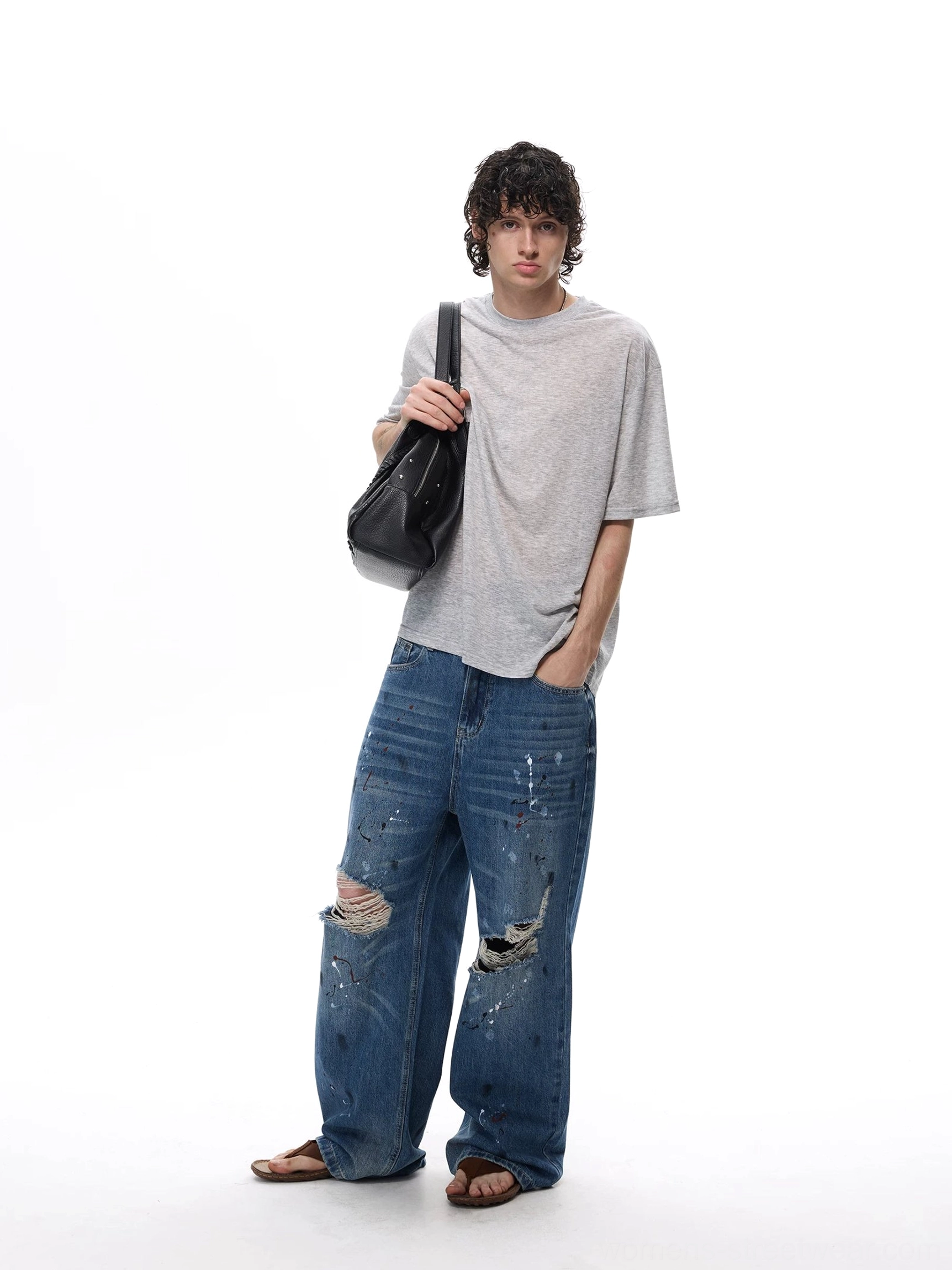 Paint splatter wide-leg jeans styled with an oversized streetwear outfit, featuring faded blue denim and shredded knees