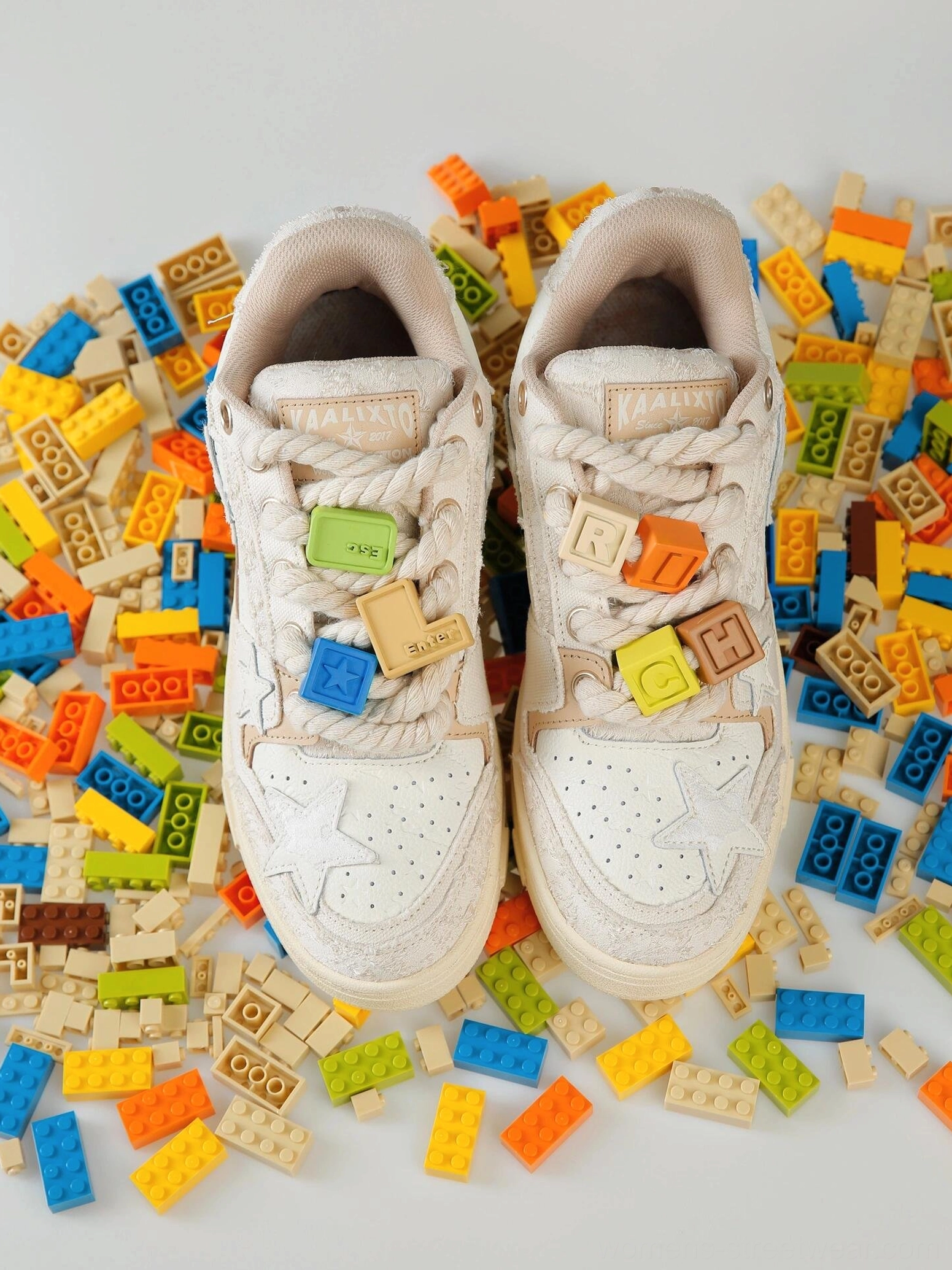 Pair of beige star low-top streetwear sneakers with matching lace charms, dimensional texture, retro star details, and chunky rope laces