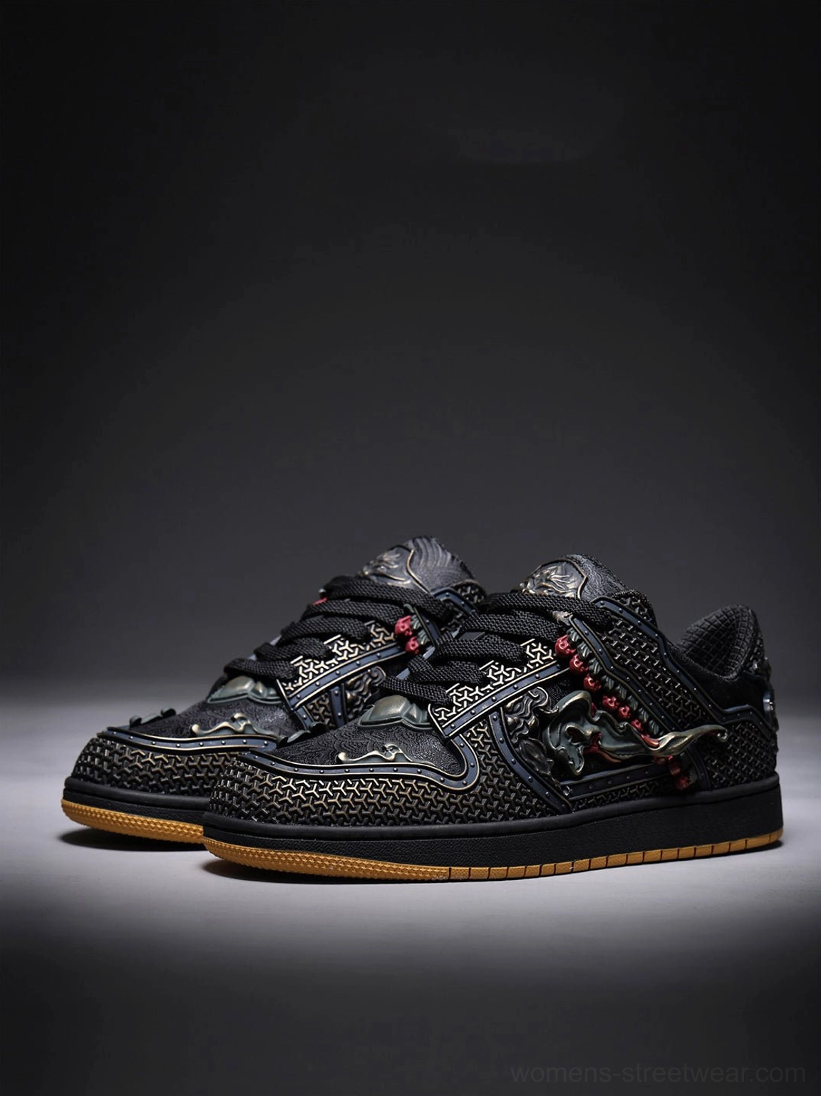 Pair of black dragon low-top sneakers with bronze embroidery, red beaded accents, perforated texture, and gum soles