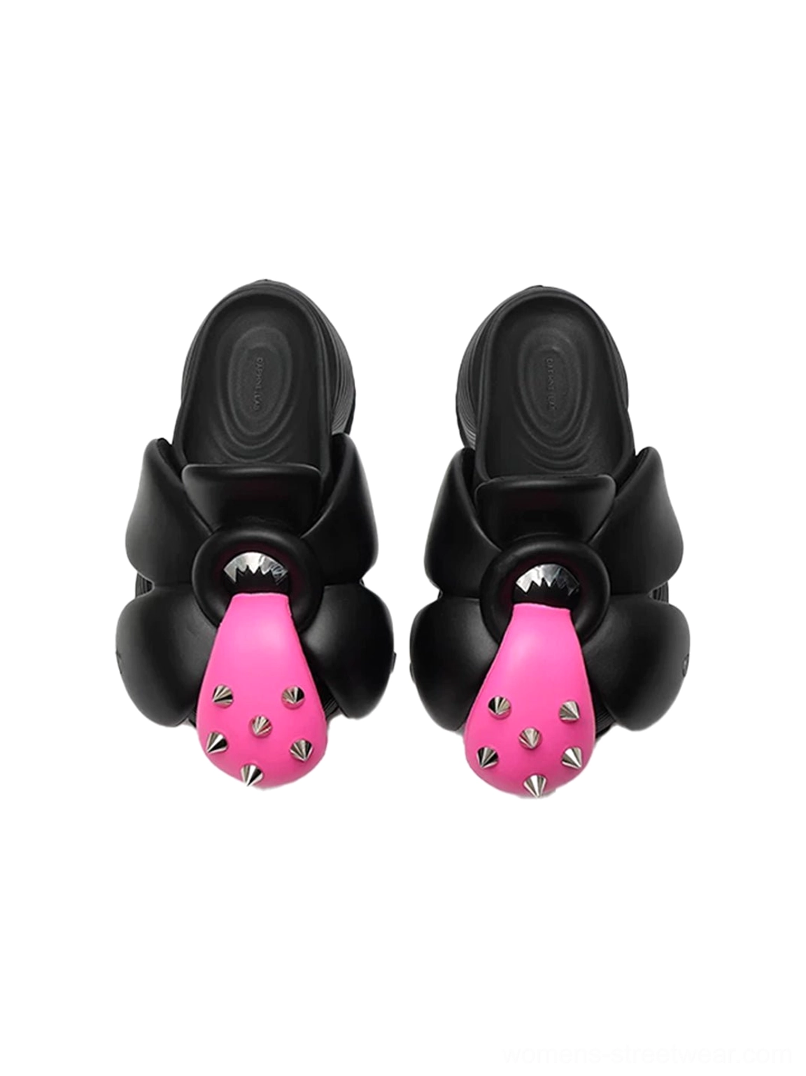 Top down flat lay of a pair of black flower platform slip-on shoes showing the sculpted floral uppers pink spike accents and insoles