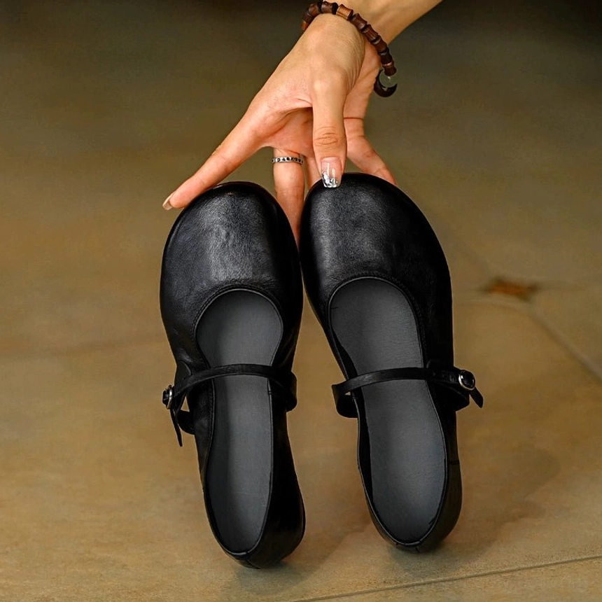 Pair of matching black leather Mary Jane flats with silver buckle ankle straps and flat insoles shown from above