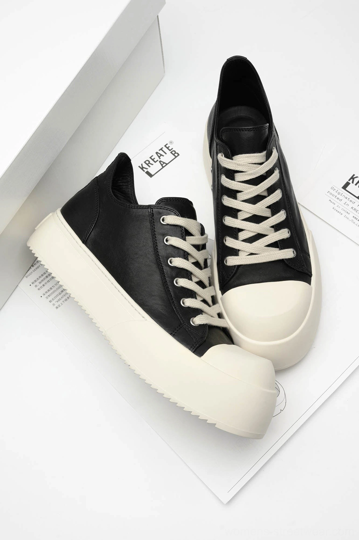 Pair of black low-top platform leather sneakers displayed from above with thick off-white soles and clean urban styling