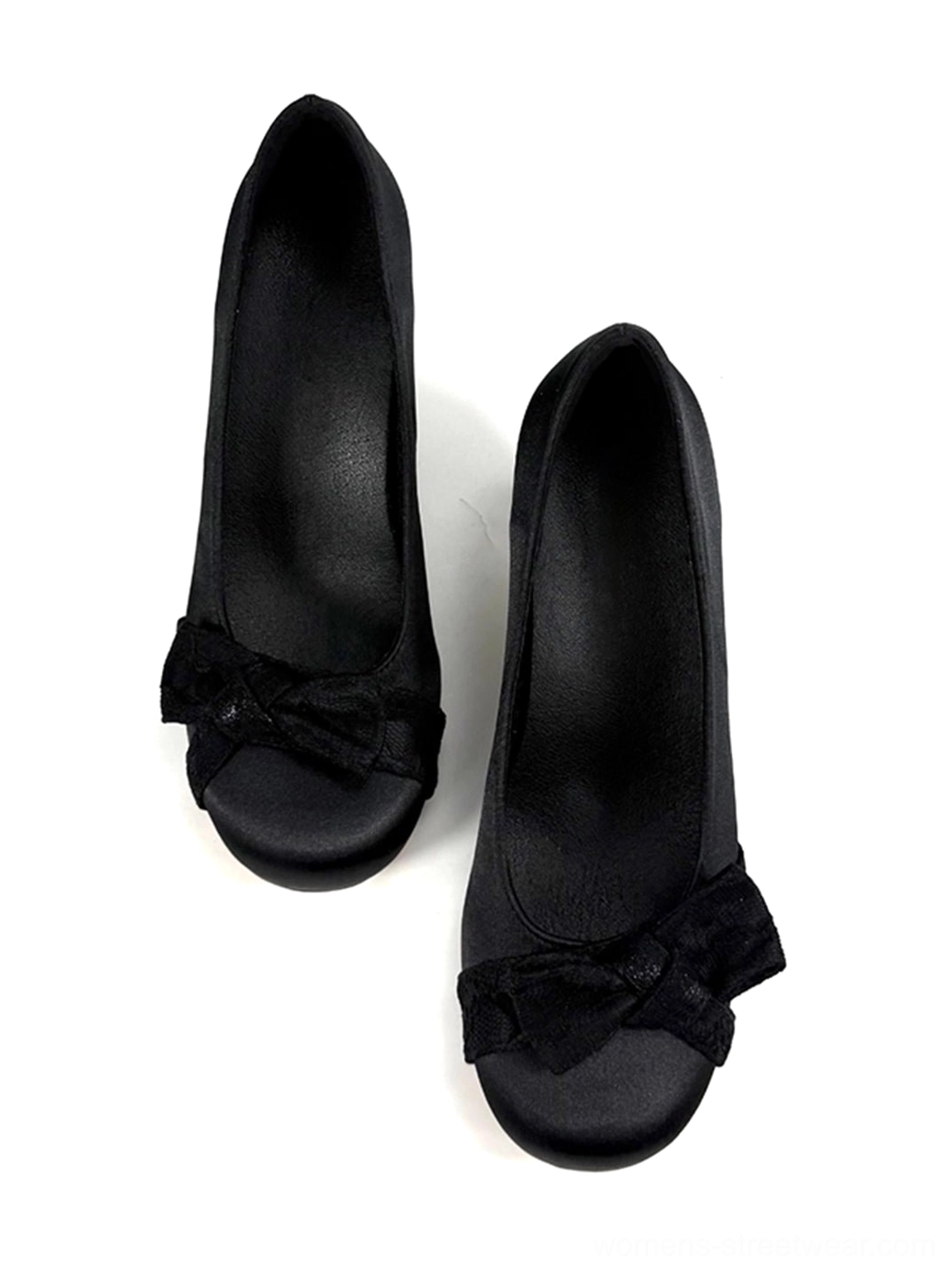 Pair of black satin-look pumps facing inward with prominent front bows, exposed lining, and rounded closed toes