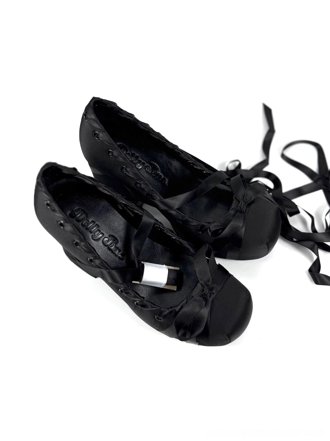 Pair of black satin ribbon lace-up platform heels shown from above with long tying straps, bow vamp accents, and elevated soles