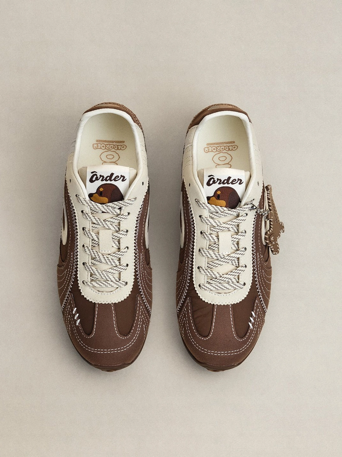Pair of brown and cream swirl panel retro trainers shown from above with lace-up design and side charms