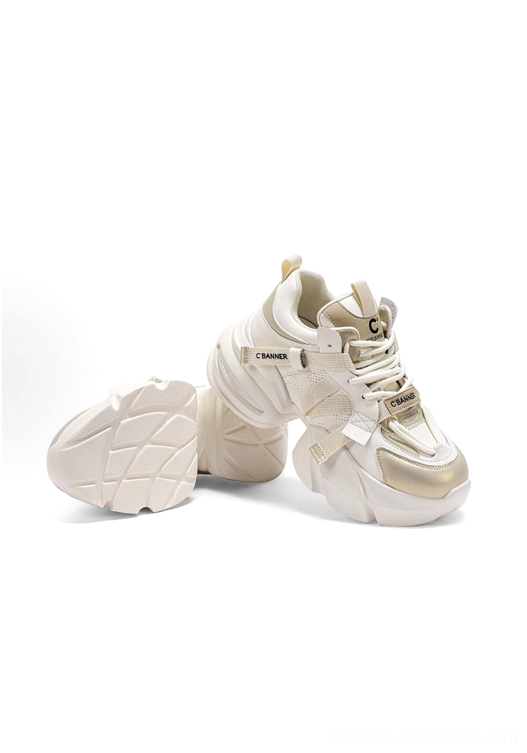 Pair of cream white stitched panel dad sneakers with one shoe tilted to reveal the textured rubber outsole