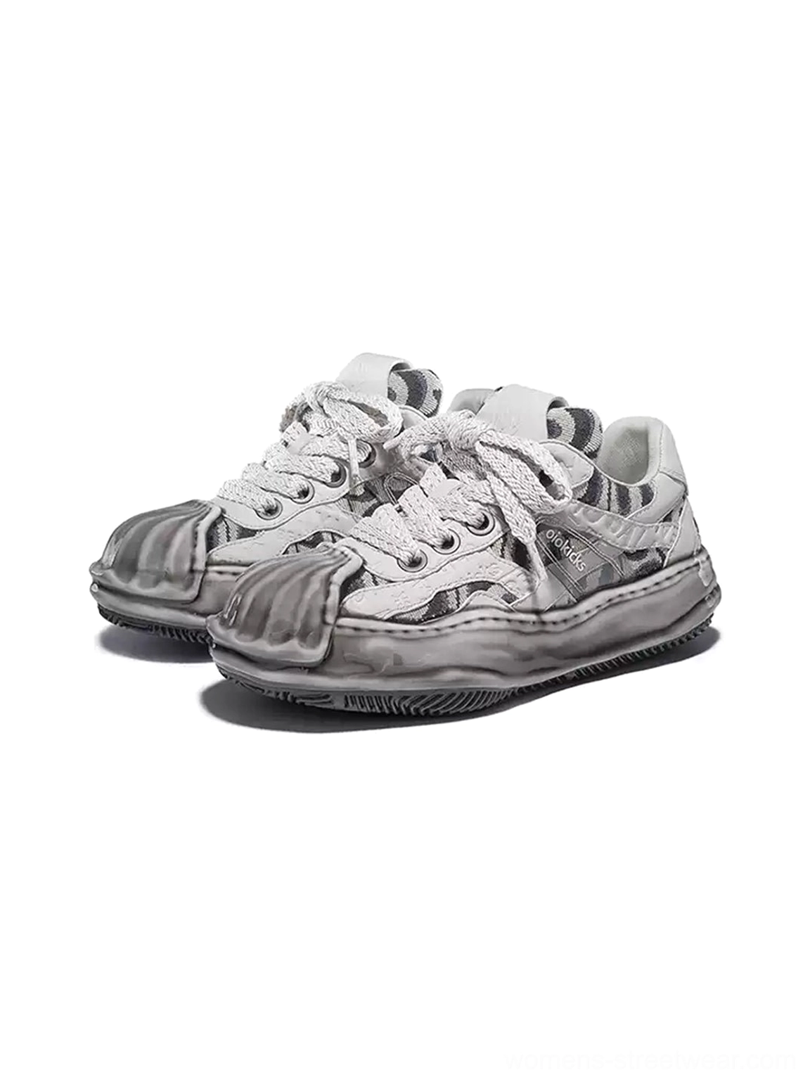 Pair of gray and white distressed camo shell-toe leather skate sneakers with weathered toe caps, chunky laces, and thick sculpted outsoles