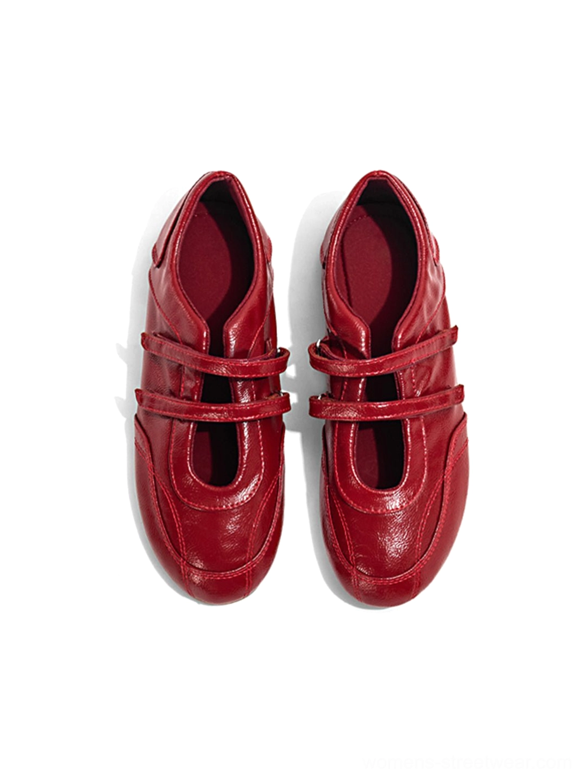 Pair of red crisscross strap leather-look flats displayed from the front on a white background