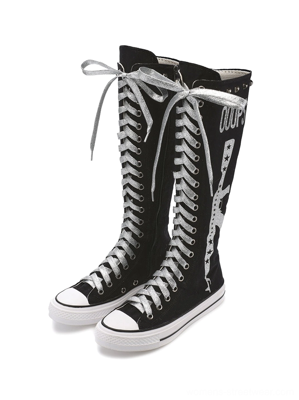 Front view of paired black studded graphic canvas knee-high boots with silver ribbon laces, rivet collar trim, printed punk graphics, and white soles