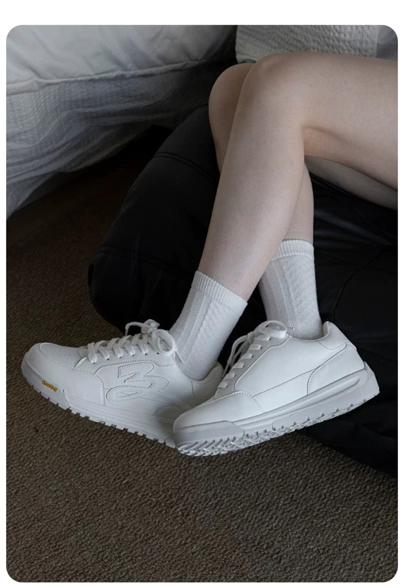 Pair of white low-top platform skate sneakers with flame embossed sides and thick textured rubber soles in an indoor lifestyle setting