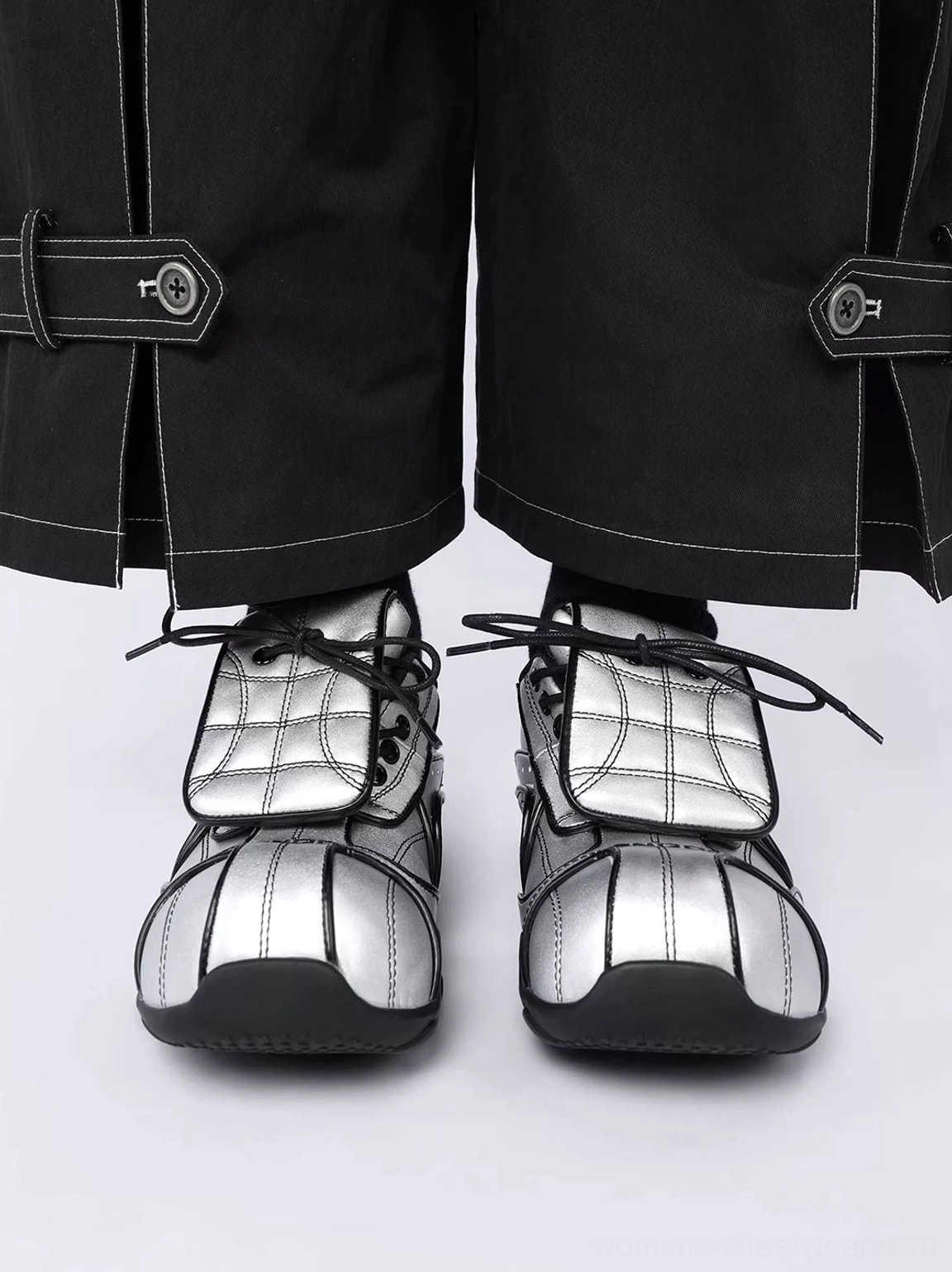 Front view of paired metallic silver quilted streetwear sneakers with symmetrical foldover tongues and black contrast-stitch cargo pants